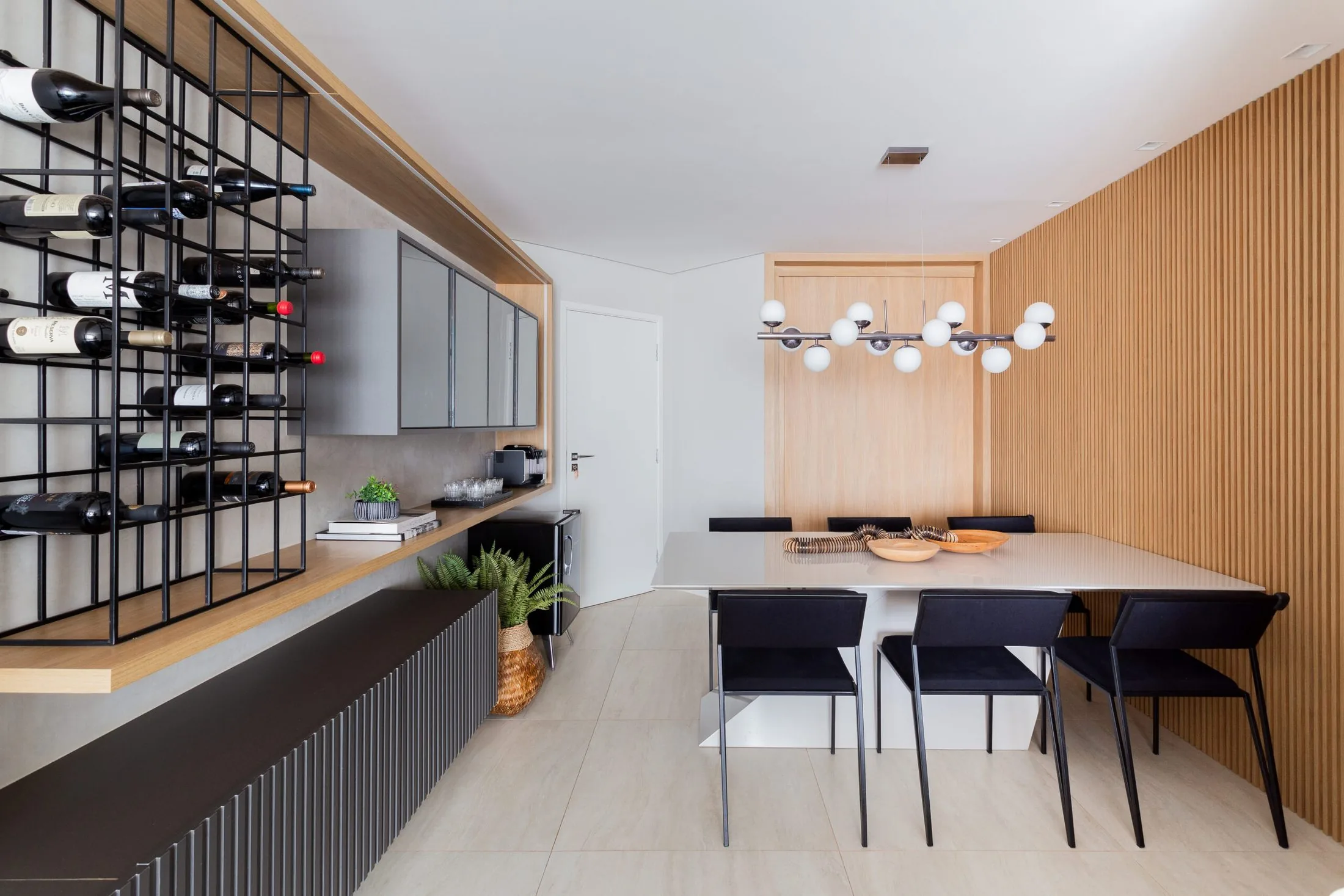Sala de jantar com adega de ferro preto, painel ripado e lustre de globos