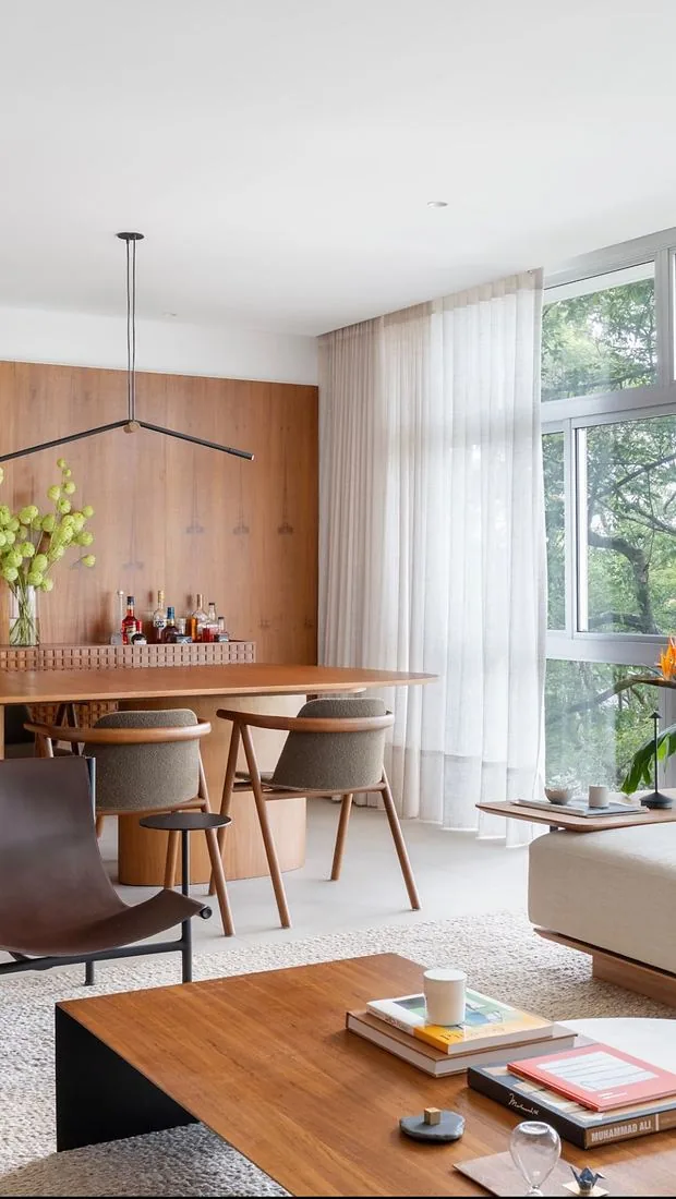 Sala integrada com mesa de jantar em madeira e cortina de linho