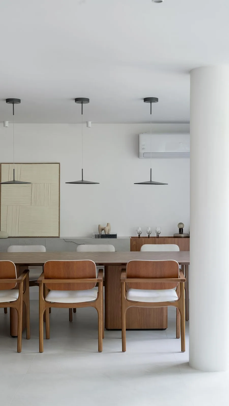 Sala de jantar com mesa de madeira, cadeiras de madeira com assento claro e pendentes cinza